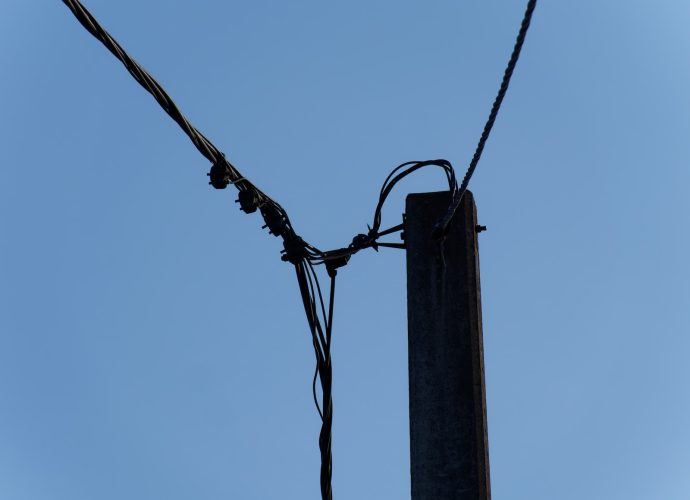 a telephone pole with wires and a blue sky in the background