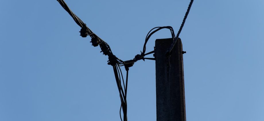 a telephone pole with wires and a blue sky in the background